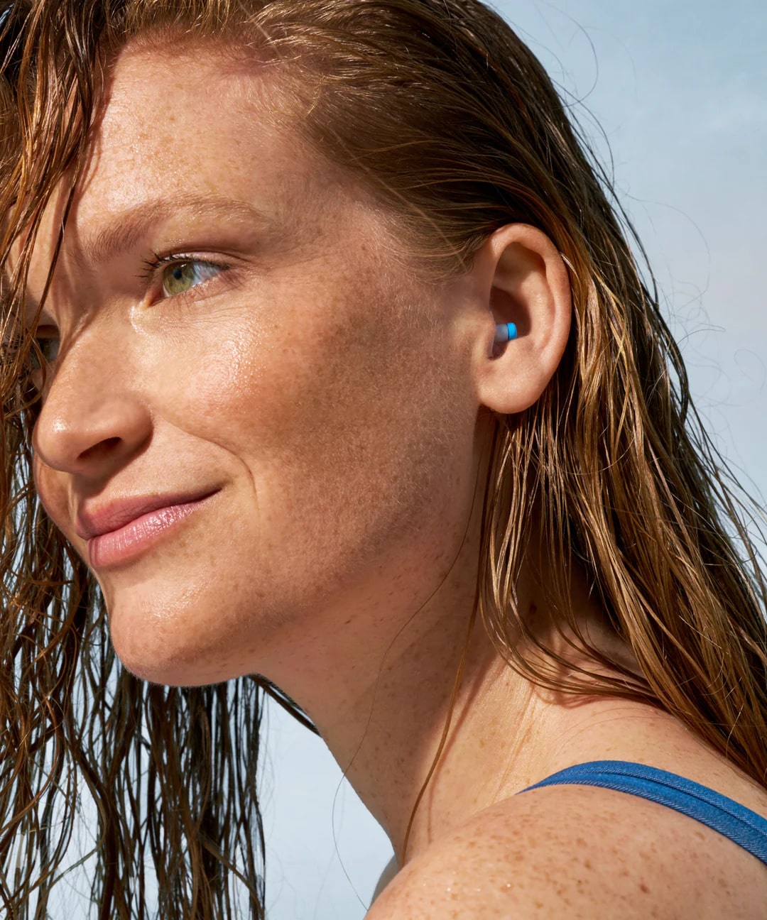 Mujer con cabello mojado usando tapones Alpine SwimSafe.